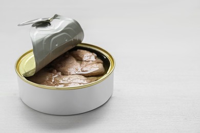 Open tin can of tasty cod liver on white wooden table, closeup. Space for text
