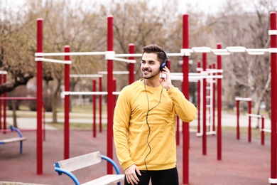 Young man with headphones listening to music on sports ground