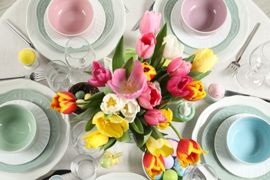 Photo of Festive Easter table setting with beautiful flowers and painted eggs, top view