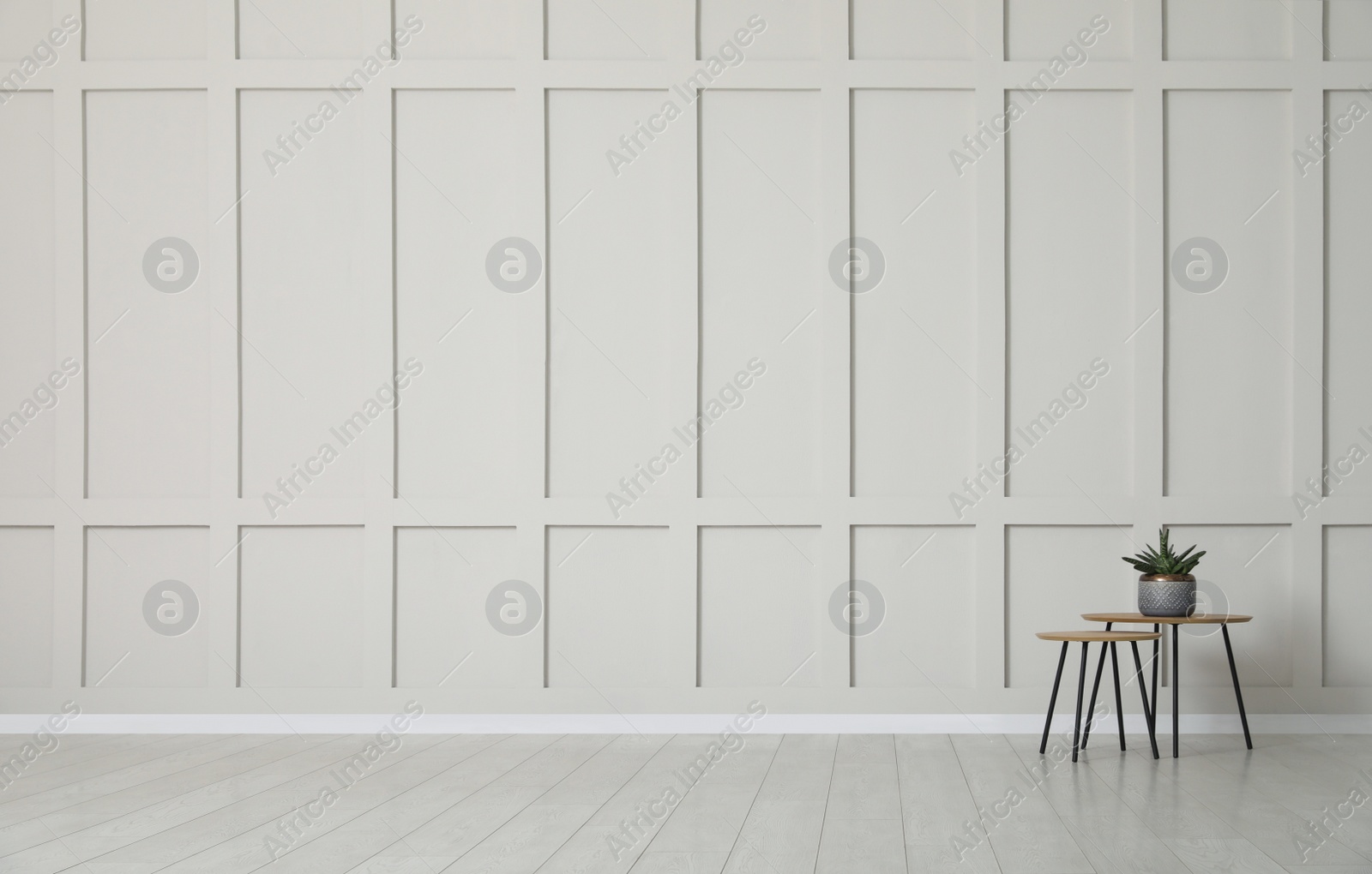 Photo of Tables with potted houseplant near empty wall indoors. Space for design