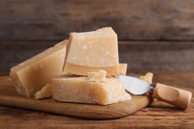 Delicious parmesan cheese with knife on wooden table, closeup