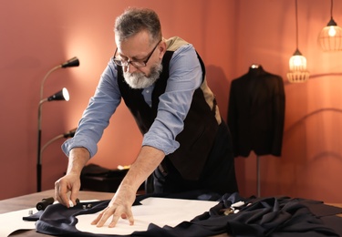 Mature tailor working with sewing pattern in atelier