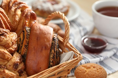Photo of Different tasty freshly baked pastries in wicker basket, closeup. Space for text