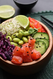 Delicious poke bowl with vegetables, fish and edamame beans on table, closeup