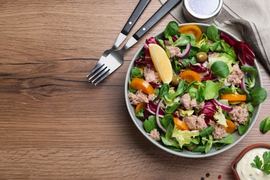 Photo of Bowl of delicious salad with canned tuna and vegetables served on wooden table, flat lay. Space for text