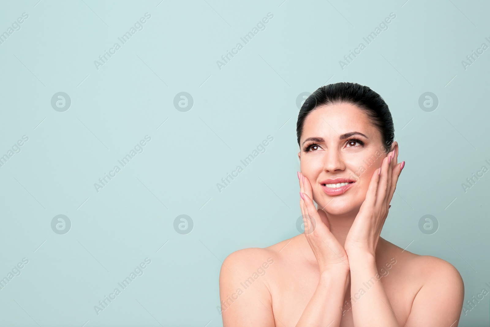 Photo of Beautiful woman with clean skin touching her face on color background