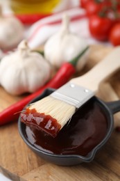 Marinade in gravy boat and basting brush on table, closeup