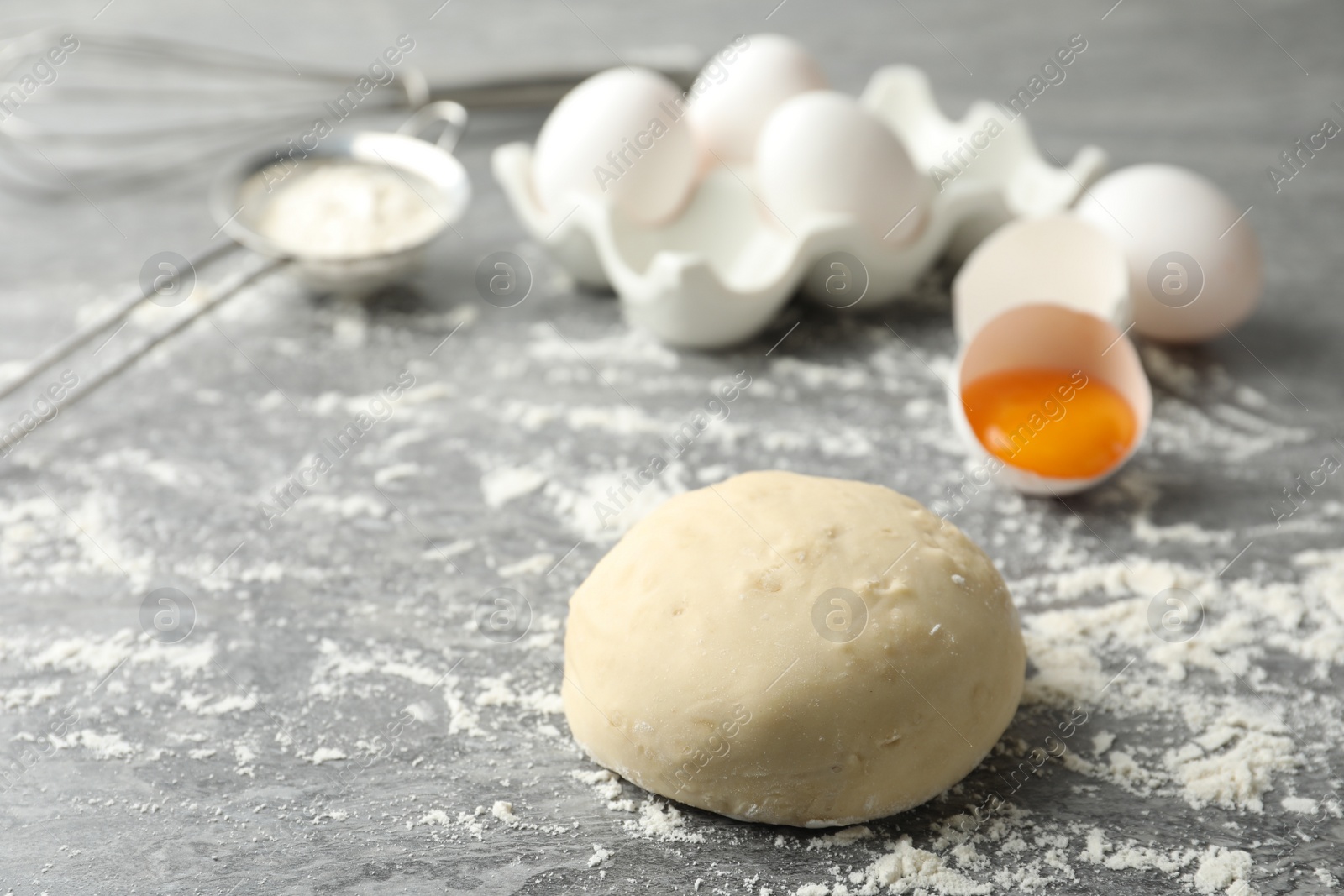 Photo of Wheat dough and products on grey table, space for text. Cooking pastries