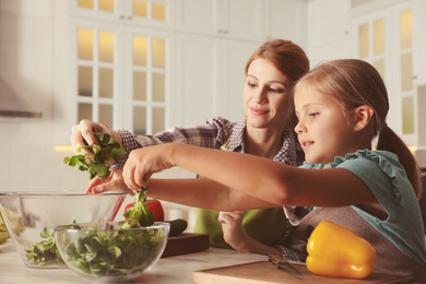 Mother and daughter cooking salad together in kitchen