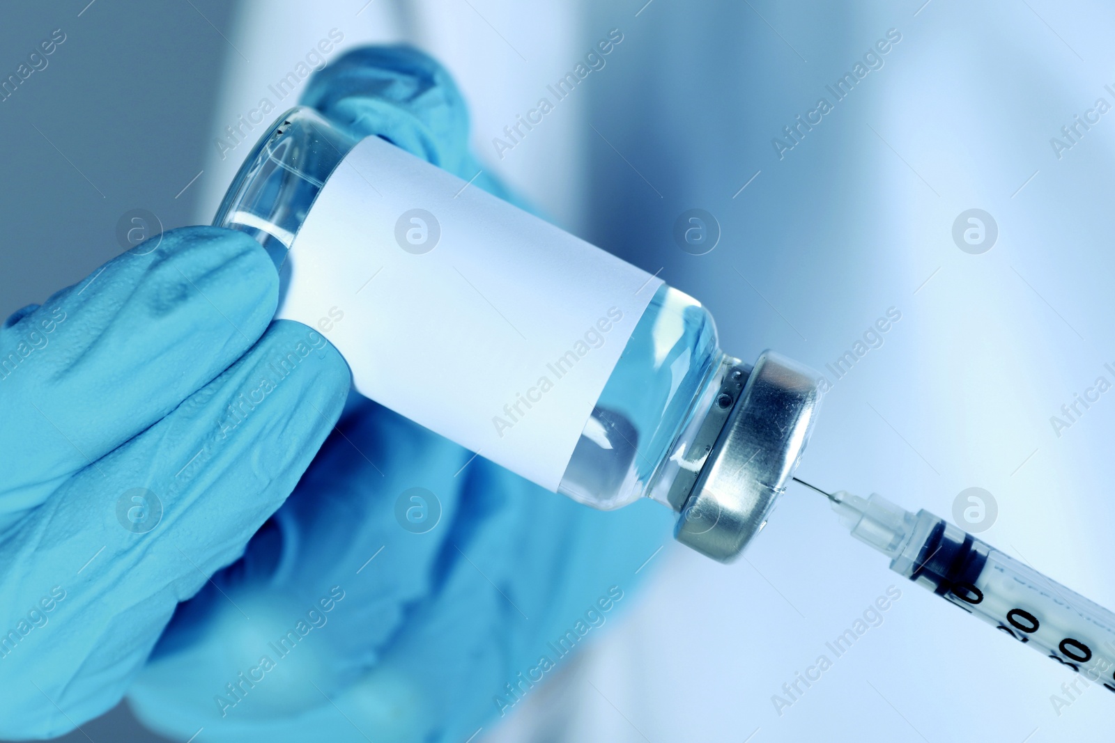 Image of Laboratory worker filling syringe with medication from glass vial, closeup