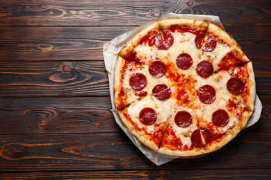 Photo of Hot delicious pepperoni pizza on wooden table, top view. Space for text