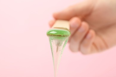 Woman holding spatula with hot depilatory wax on light background, closeup