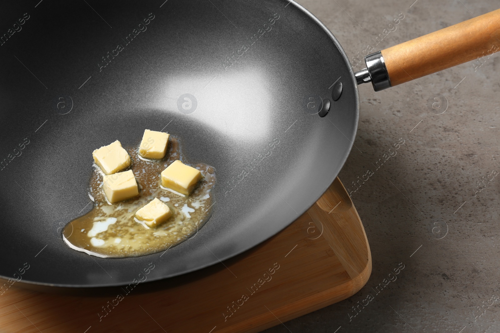 Photo of Frying pan with melting butter on grey table, closeup
