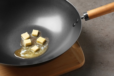 Frying pan with melting butter on grey table, closeup