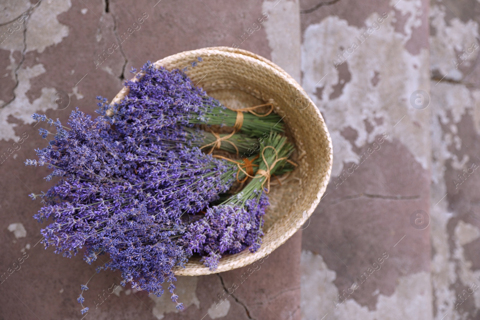 Photo of Wicker basket with lavender flowers on cement floor outdoors, top view. Space for text