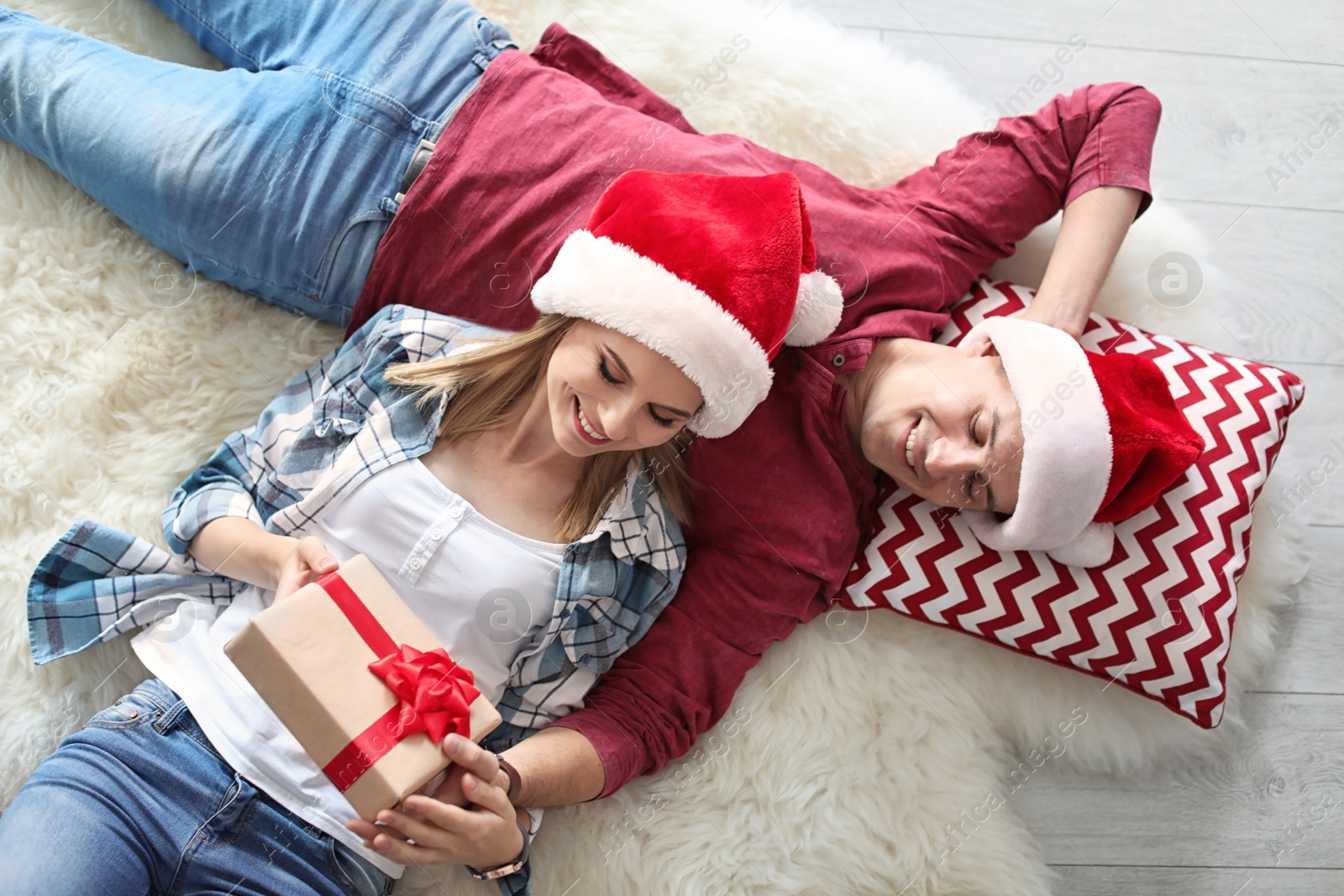 Photo of Young couple with Christmas gift at home