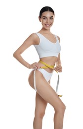 Photo of Young woman measuring waist with tape on white background