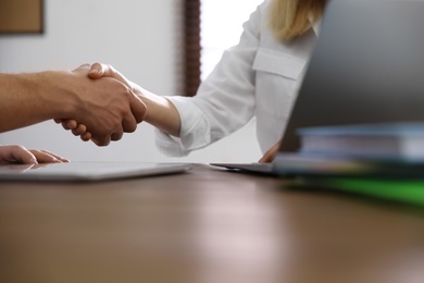 Photo of Business partners shaking hands at table after meeting, closeup. Space for text