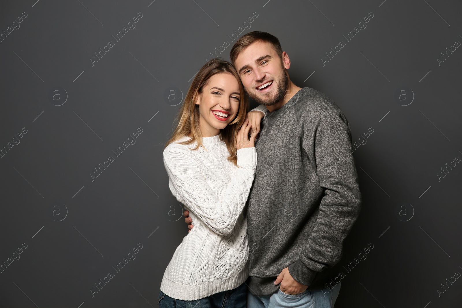 Photo of Young couple in warm sweaters on dark background