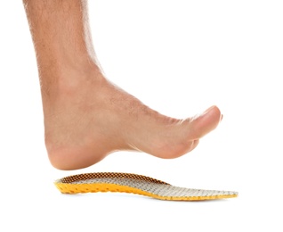 Man fitting orthopedic insole on white background, closeup. Foot care