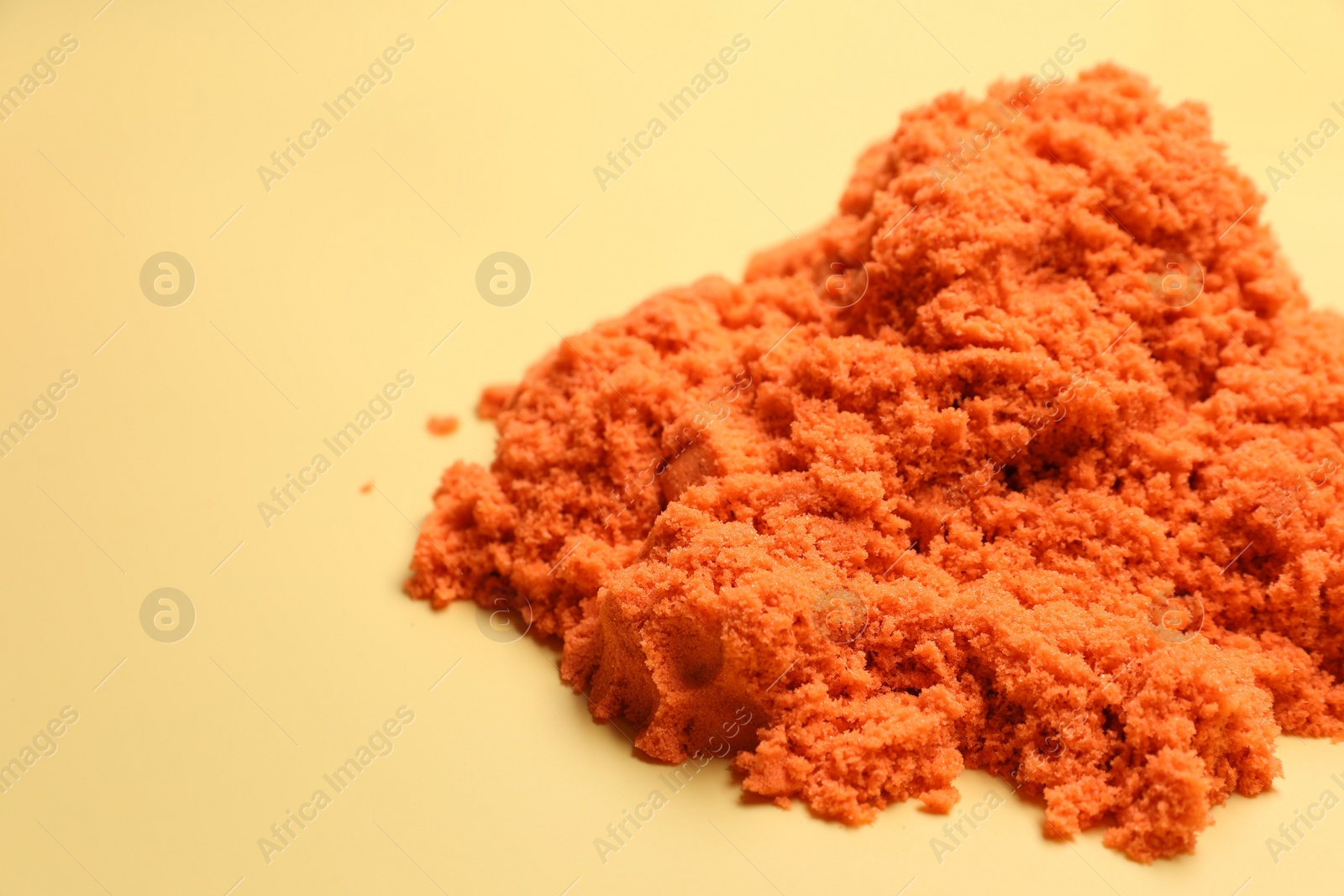 Photo of Pile of orange kinetic sand on beige background, space for text