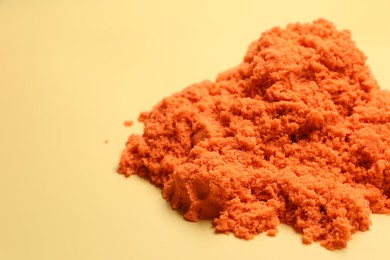 Pile of orange kinetic sand on beige background, space for text