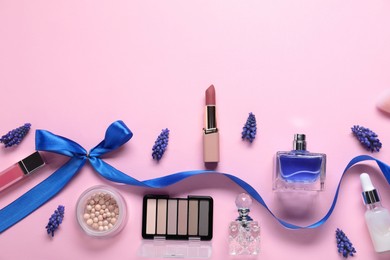 Flat lay composition with different makeup products and beautiful spring flowers on pink background. Space for text