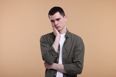 Portrait of sad man on beige background