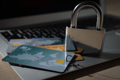 Credit cards, lock and laptop on wooden table, closeup. Cyber crime
