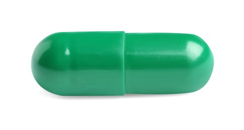 One green pill on white background. Medicinal treatment