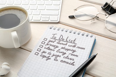 Photo of Notebook with to do list on white wooden table