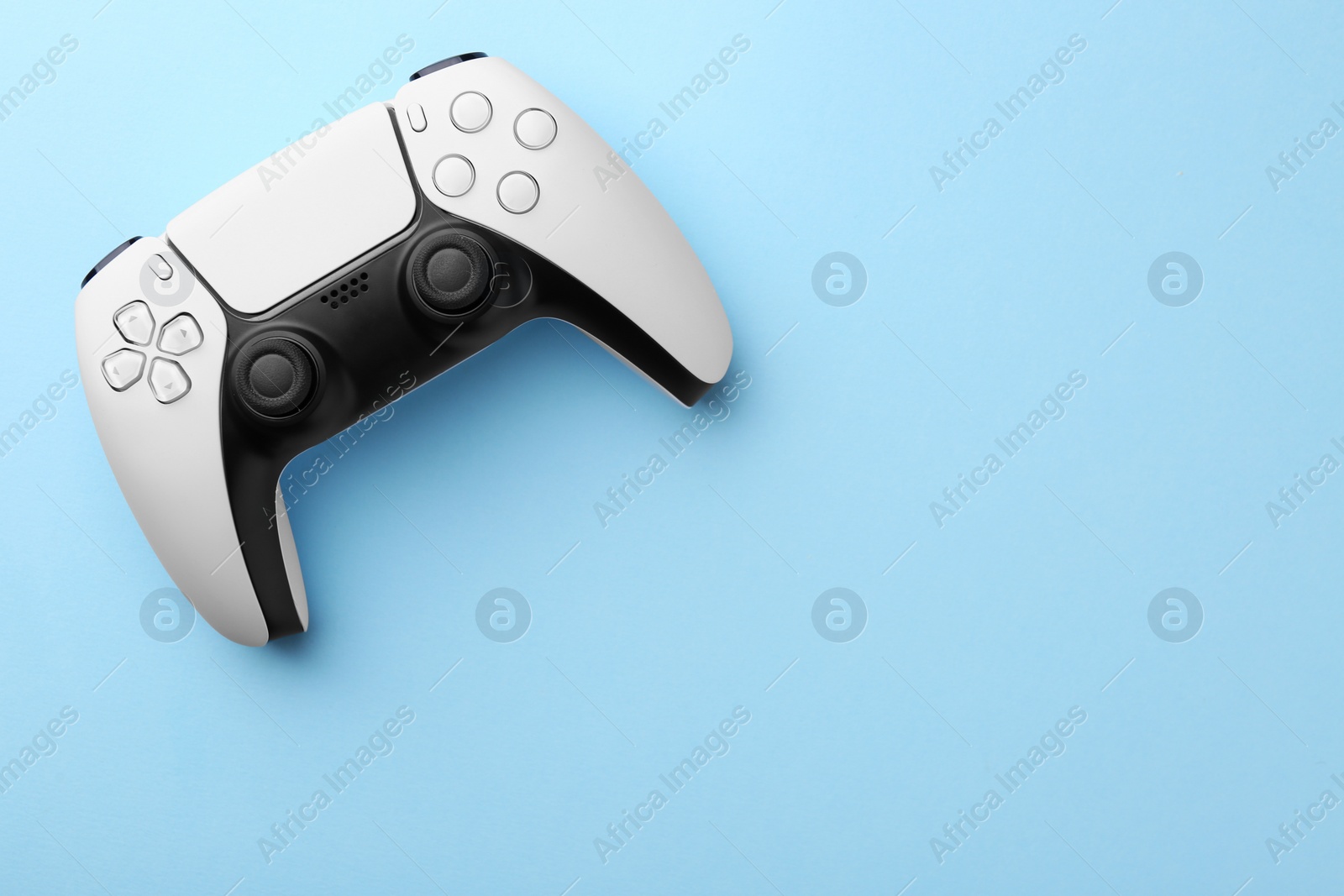 Photo of Wireless game controller on light blue background, top view. Space for text