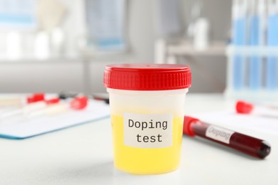 Photo of Jar with urine sample on white table indoors. Doping control