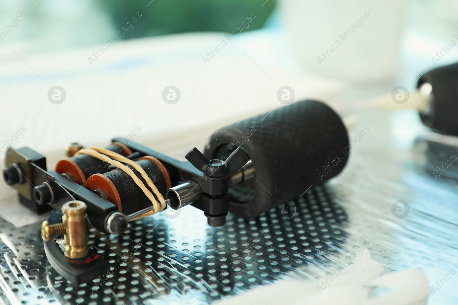 Photo of Modern professional tattoo machine on table in salon