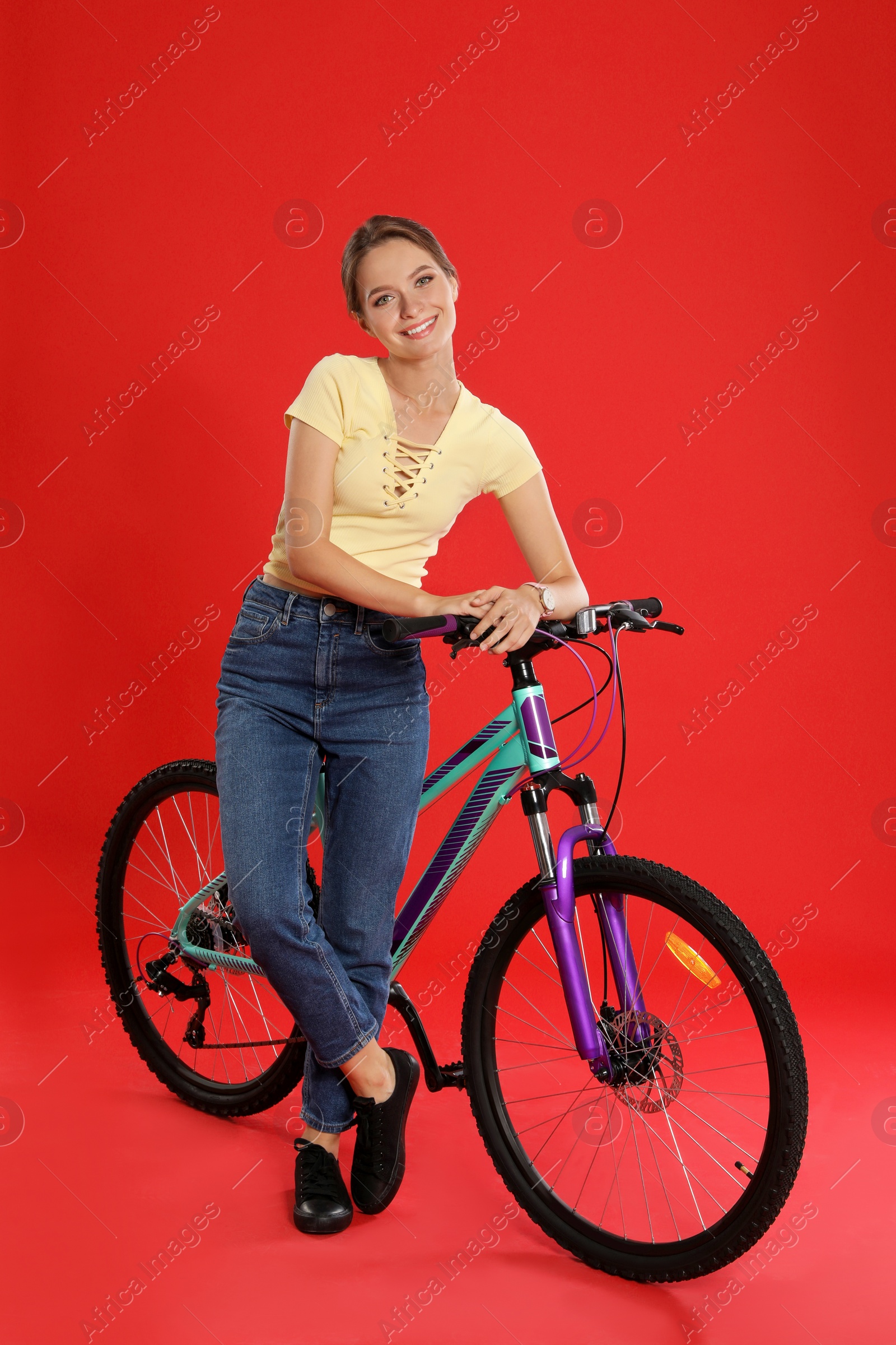 Photo of Happy young woman with bicycle on red background