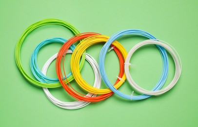 Photo of Colorful plastic filaments for 3D pen on green background, flat lay