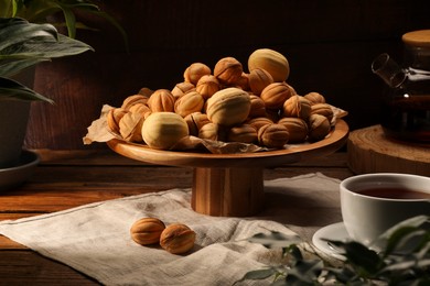 Photo of Aromatic walnut shaped cookies and tea on wooden table. Homemade pastry carrying nostalgic atmosphere