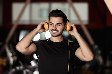 Young man listening to music with headphones at gym