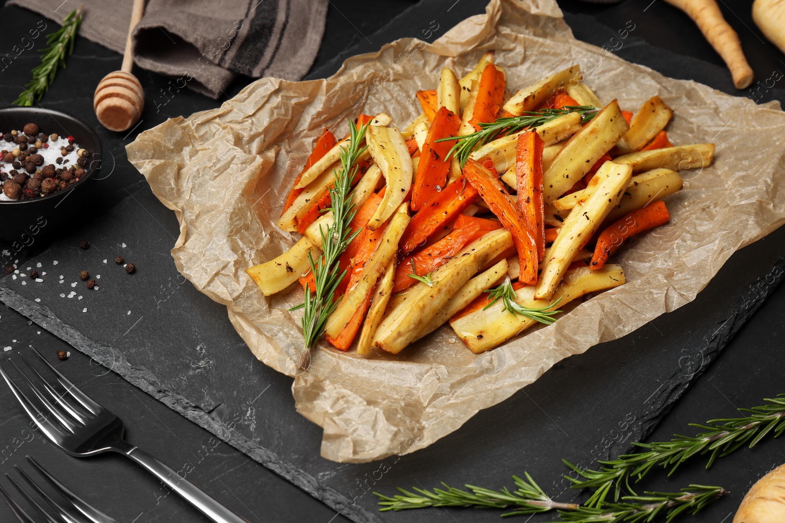 Photo of Tasty baked parsnip and bell pepper served on dark grey table