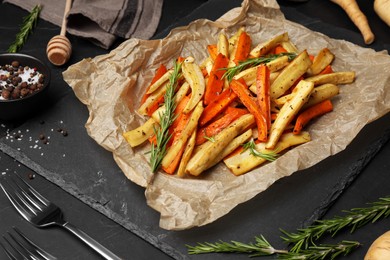 Tasty baked parsnip and bell pepper served on dark grey table