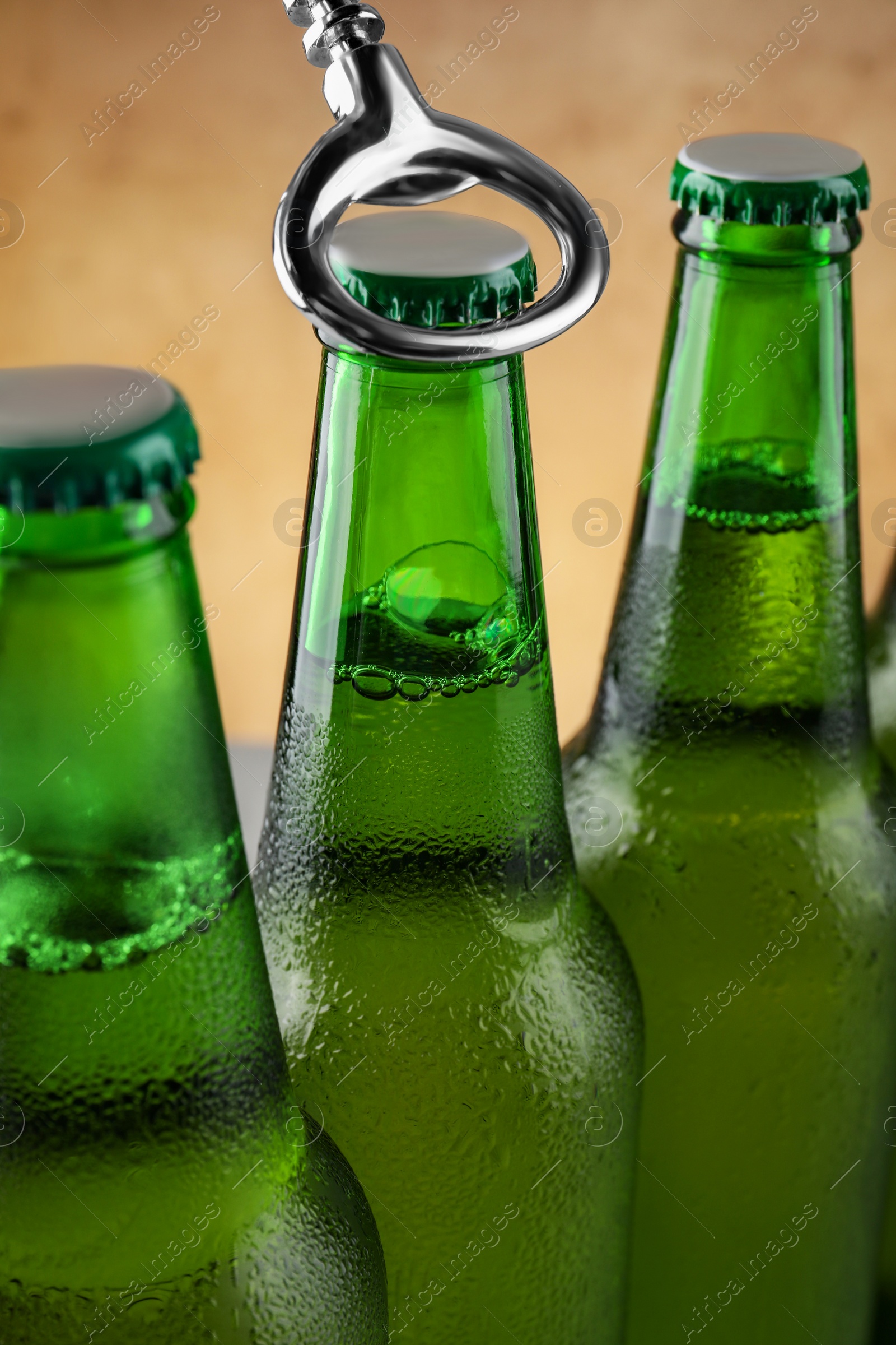 Photo of Opening bottle of beer on light brown background, closeup