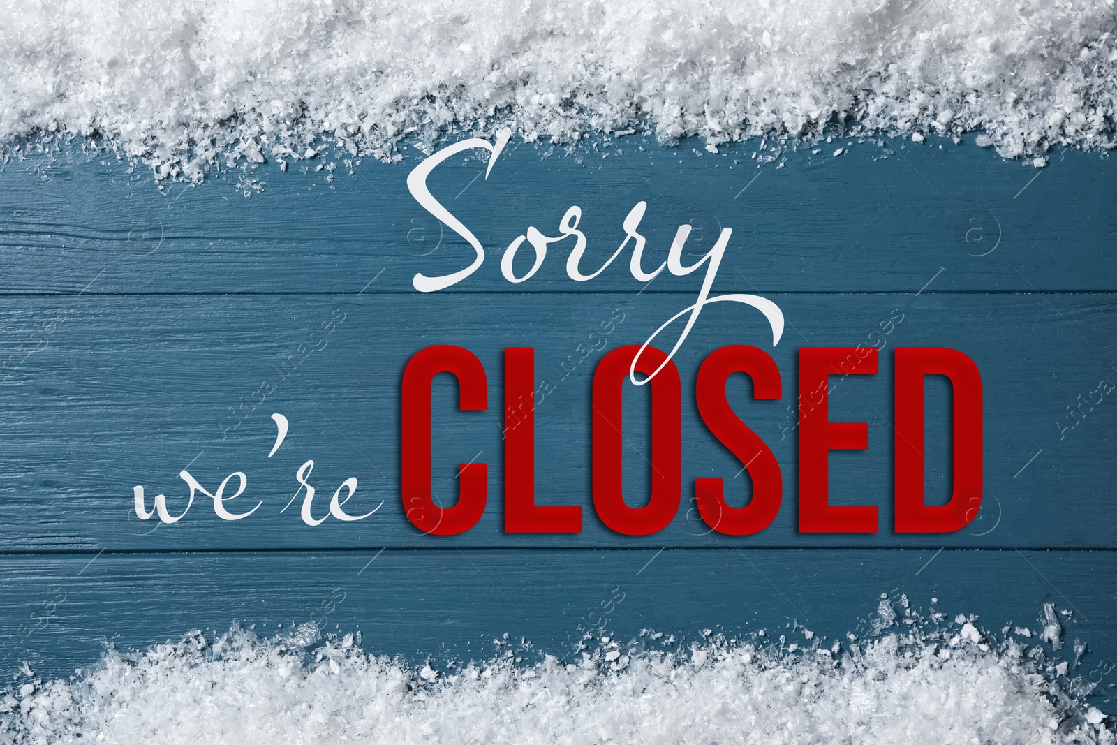 Image of Sorry we are closed sign. Text and snow on light blue wooden background