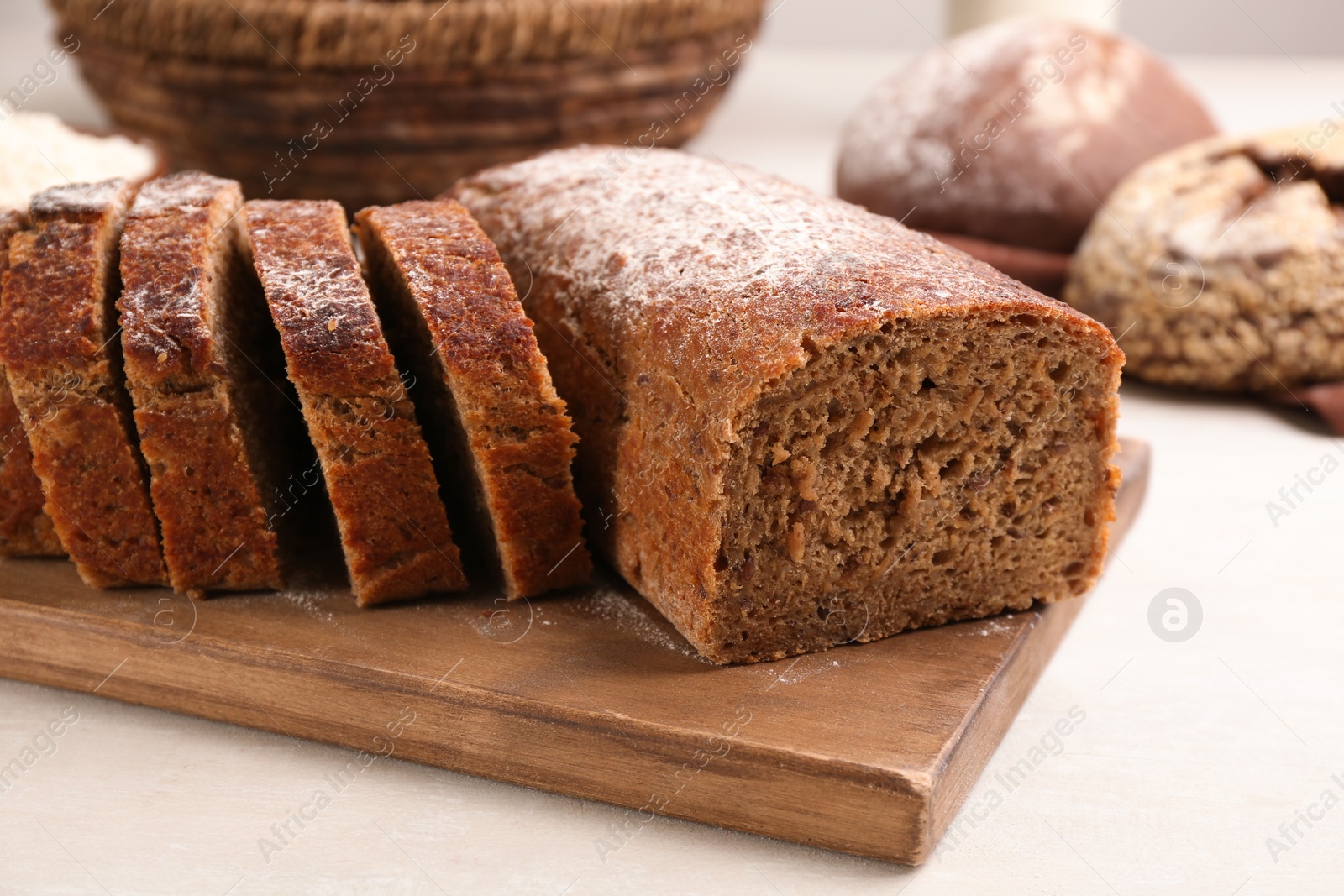 Photo of Cut freshly baked bread on white wooden table, closeup