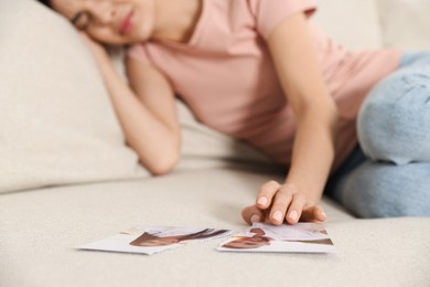 Photo of Upset woman with parts of torn photo on sofa, selective focus. Divorce concept
