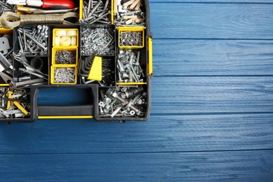 Photo of Plastic box with different furniture fittings and tools on blue wooden table, top view. Space for text