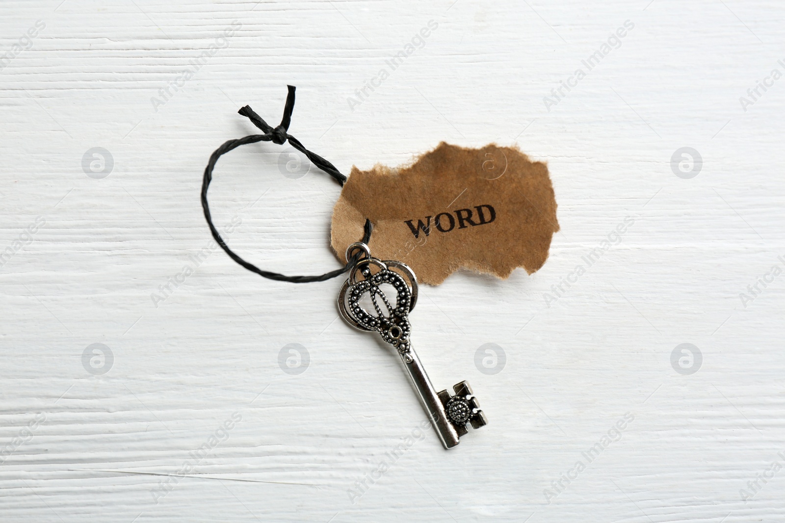 Photo of Key with tag WORD on white wooden background, top view. Keyword concept