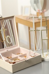 Photo of Jewelry box with many different accessories and stand on light grey table indoors