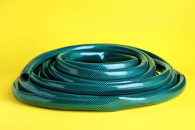 Photo of Green rubber watering hose on yellow background