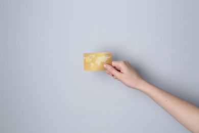 Woman holding credit card on light grey background, closeup