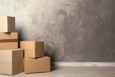 Photo of Cardboard boxes on floor near color wall. Mockup for design